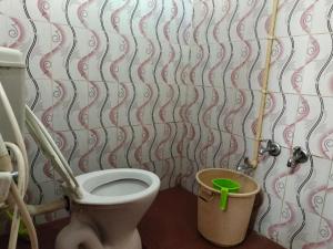 a bathroom with a toilet and a trash can at Coorg Kusuma's budget homes in Madikeri