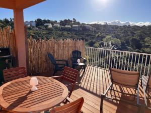 a wooden deck with a table and chairs on a balcony at Appartement 2 chambres, mezzanine et piscine in Porto-Vecchio