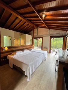 1 dormitorio con 1 cama blanca grande en una habitación en Hospedaria Vila Serra da Luz, en Pindamonhangaba