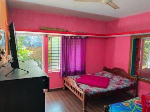 a bedroom with pink walls and a bed and a desk at Coorg Kusuma's budget homes in Madikeri