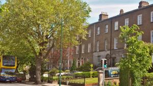 een gele dubbeldekkerbus geparkeerd voor een gebouw bij Waterloo Lodge in Dublin