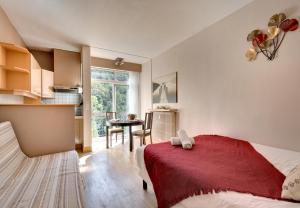 Cet appartement comprend une chambre avec un lit et une table ainsi qu'une cuisine. dans l'établissement Hôtel Les Sources, à Vernet-les-Bains