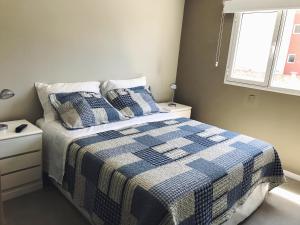 1 dormitorio con 1 cama con manta a cuadros en Departamentos Aguado -Depto A con PARRILLA 1dorm - Alquileres RV en Bahía Blanca