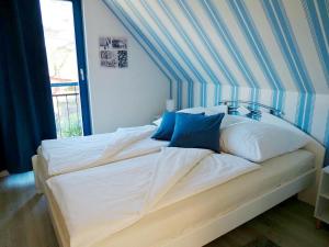 een groot wit bed met blauwe kussens in een slaapkamer bij Meeresrauschen 1 in Groß Kirr
