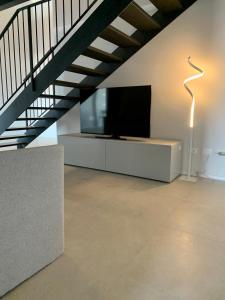 a living room with a flat screen tv and a floor lamp at Panorama Loft Apartments in Stresa
