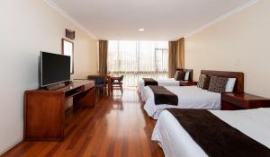 a hotel room with three beds and a flat screen tv at Hotel NASS Pinar del Lago in Cuenca