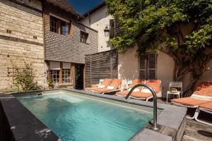 a swimming pool with chairs and a building at Le Champ des Oiseaux & Spa in Troyes