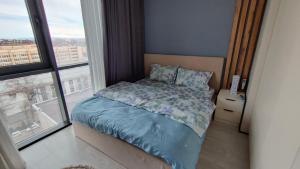 um quarto com uma cama com um edredão azul e uma janela em ЖК Akay city. Новый ремонт em Tashkent