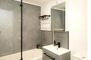 une salle de bain avec un lavabo, une baignoire et un miroir dans l'établissement Promenade View - seafront hideaway, à Eastbourne 16 autres photos