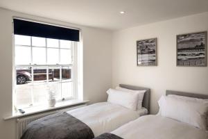 two beds sitting next to a window in a bedroom at Promenade View - seafront hideaway in Eastbourne
