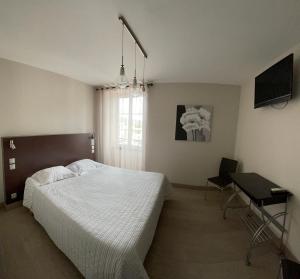 a bedroom with a bed and a desk and a television at Hotel Mendy in Saint-Jean-le-Vieux