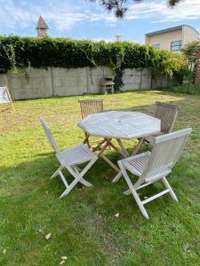 a picnic table and two chairs in a yard at Le Presbytère des Baraques à Blériot-Plage - Apt 3 in Sangatte