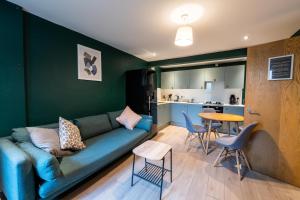 a living room with a blue couch and a kitchen at Aaron Wise - 17 Fitzhamon Apartments in Cardiff