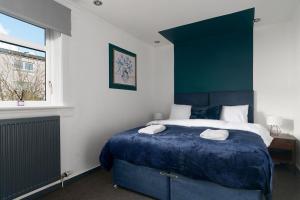 a bedroom with a blue bed with two towels on it at Cumbernauld Haven Hideout Sleeps upto 7 in Cumbernauld