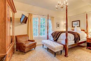 a bedroom with a bed and a chair and a television at Portland's White House Carriage House in Portland