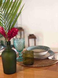 une table avec un vase vert avec des fleurs et un bol dans l'établissement 1221 apartment, à Roger
