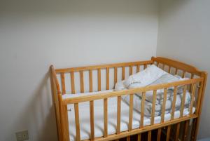 ein Kinderbett in einem Zimmer mit einer weißen Wand in der Unterkunft TENT OKAYAMA - 3 bedrooms, 10 min walk from Okayama Station in Hokancho
