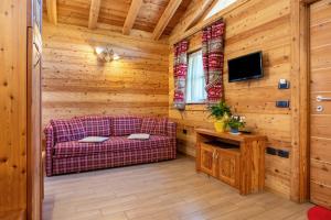 a living room with a purple couch in a wooden room at Chalet Camping Faè 3 in Madonna di Campiglio