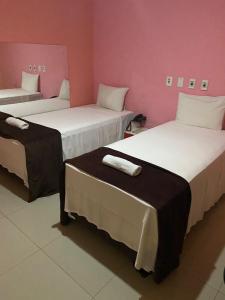 2 camas en una habitación con paredes rosas en Hotel Aliança, en Salvador