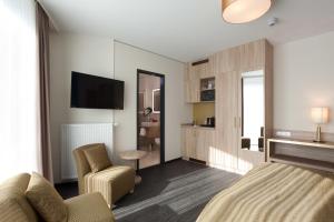 a bedroom with a bed and a chair and a tv at Stay! Hotel Boardinghouse in Hamburg