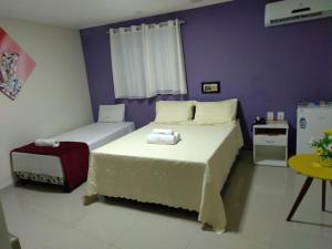 1 dormitorio con 2 camas y pared púrpura en Hotel Aliança, en Salvador