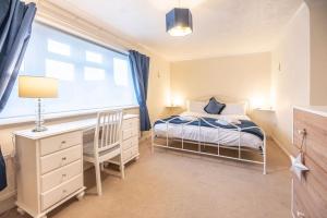 a bedroom with a bed and a desk and a window at 4 The Sandlings in Aldeburgh