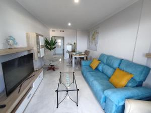 Una sala de estar con un sofá azul y un televisor. en Mojácar beach increíbles vistas Arniel, en Mojácar