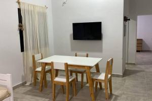 a dining room table with chairs and a tv on a wall at Cerros de Cafayate, Casa Nº1 in Cafayate