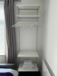 a white closet with white shelves and a bed at Ferrers House in Doncaster