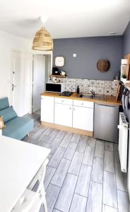 a kitchen with blue walls and white cabinets at Appartement proche de l'aéroport de Nantes in Saint-Aignan-Grand-Lieu