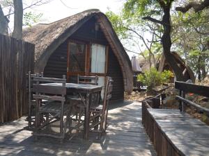 a cabin with a thatched roof with a table and chairs at Geo Trail Lodge and Spa in Barberton