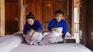 dwoje osób siedzących na łóżku w obiekcie Homestay Yến Long w mieście Lạng Sơn
