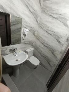 La salle de bains est pourvue d'un lavabo, de toilettes et d'un miroir. dans l'établissement SAFAR hotel, à Tachkent