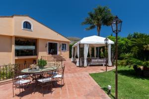 a patio with a table and chairs and an umbrella at Villa lady olimpia in Palermo