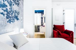 una camera con un letto bianco e una sedia rossa di La Bella Vita - In Blu a Sottomarina