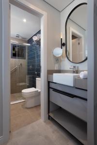 a bathroom with a sink and a toilet and a mirror at Brava Mundo Hotel Boutique OFICIAL in Itajaí