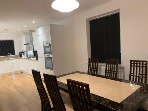 Brand New Entire 4 Bed House Multiple Free Parking Early Check-in Late Check- Out Allowed في South Ockendon: مطبخ وغرفة طعام مع طاولة وكراسي