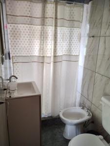 y baño con cortina de ducha blanca, aseo y lavamanos. en Sankofa Cabañas en Yacanto