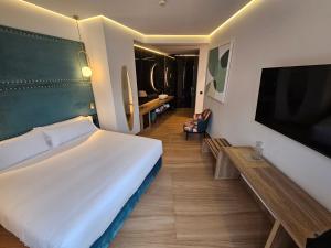 a bedroom with a large bed and a flat screen tv at Hotel Las Tres Campanas in Badajoz