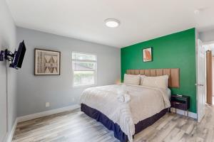 a bedroom with a green accent wall and a bed at BayCation in Tampa