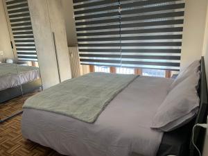 een bed in een slaapkamer met een raam met jaloezieën bij OASI ZEN VARESE - Tra laghi e monti - in Varese