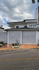a white house with two garage doors on a street at Casa próximo do aeroporto de Brasília in Brasilia