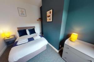 a bedroom with a bed with blue walls and two lamps at Stockton House in Stockton-on-Tees