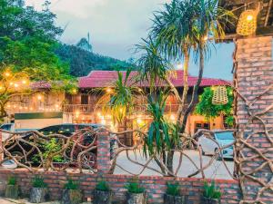 a patio with chairs and palm trees in front of a building at Homestay Yến Long in Lạng Sơn