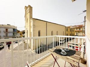 balcón con mesa y vistas a la calle en Portosalvo Holiday House, en Marina di Ragusa