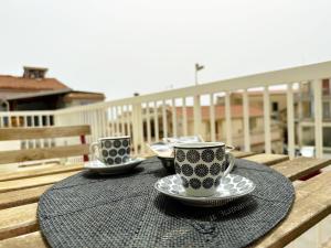 dos tazas y platillos en una mesa en un balcón en Portosalvo Holiday House, en Marina di Ragusa