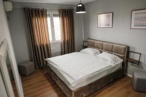 a bedroom with a bed with white sheets and a window at Urban Hotel in Tirana