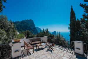 balcón con banco, mesa y sillas en Villa La Baika - Pool Panoramic views, en Capri