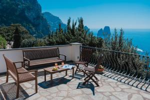 un patio con 2 sillas, un banco y una mesa en Villa La Baika - Pool Panoramic views, en Capri