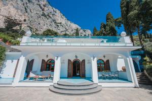 una casa blanca con una montaña en el fondo en Villa La Baika - Pool Panoramic views, en Capri